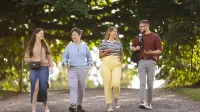 Ochrona środowiska | Uniwersytet WSB Merito Szczecin: Czworo studentów spaceruje alejką w parku, rozmawiając i uśmiechając się.