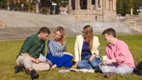 Ochrona środowiska | Uniwersytet WSB Merito Szczecin: Grupa studentów siedzi na trawie i wspólnie uczy się z książek w plenerze.