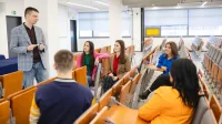 Psychologia dzieci i młodzieży | Studia jednolite magisterskie w Szczecinie | Uniwersytet WSB Merito Szczecin: Wykładowca rozmawia ze studentami w auli, prowadząc swobodne zajęcia w małej grupie.