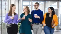 Edukacja i rehabilitacja osób z niepełnosprawnością intelektualną | Uniwersytet WSB Merito Szczecin: Czworo studentów idzie korytarzem uczelni, rozmawiając i śmiejąc się.