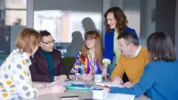 Business Intelligence – analiza danych | Studia podyplomowe w Szczecinie | Uniwersytet WSB Merito Szczecin: Grupa osób dyskutuje przy stole w sali konferencyjnej.