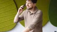 Menedżer logistyki | Uniwersytet WSB Merito Szczecin: Student rozmawia przez telefon w nowoczesnej przestrzeni uczelni, z laptopem i notatkami na biurku.