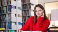 Psychologia menedżera | Studia I stopnia w Szczecinie | Uniwersytet WSB Merito Szczecin: Studentka siedzi w bibliotece, czytając książkę.