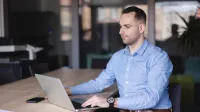 Data Science i Analiza Danych | Studia I stopnia w Szczecinie | Uniwersytet WSB Merito Szczecin: Mężczyzna pracuje przy laptopie w nowoczesnej sali konferencyjnej, skupiony na ekranie.