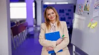 Kadry i płace | Studia podyplomowe w Szczecinie | Uniwersytet WSB Merito Szczecin: Kobieta z teczką i markerem stoi przy tablicy.