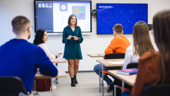 Sztuczna inteligencja w biznesie | Studia podyplomowe w Szczecinie | Uniwersytet WSB Merito Szczecin: Studentka Uniwersytetu WSB Merito prowadzi prezentację w sali wykładowej, a pozostali studenci słuchają jej wystąpienia.