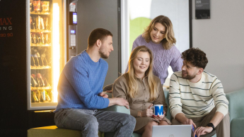 Bezpieczeństwo w biznesie i administracji | Studia I stopnia w Szczecinie | Uniwersytet WSB Merito Szczecin: Grupa studentów pracuje wspólnie przy laptopie prowadząc luźną rozmowę.