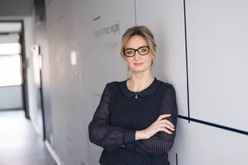Organizacja studiów | Uniwersytet WSB Merito Szczecin: Uczestniczka studiów MBA opiera się o ścianę na korytarzu uczelni- Uniwersytet WSB Merito w Szczecinie 