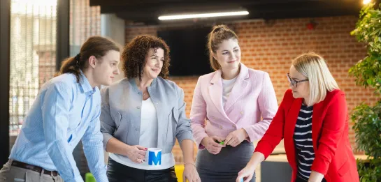 Studia podyplomowe w Szczecinie | Uniwersytet WSB Merito Szczecin: Grupa czterech osób pracuje wspólnie przy stole w biurze.