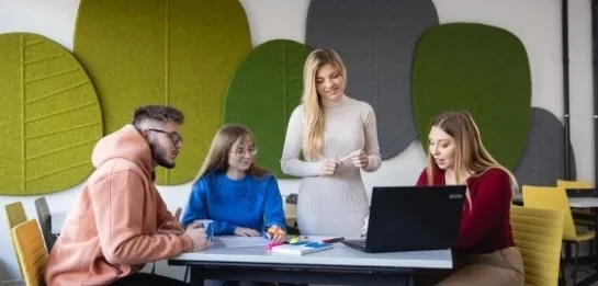 Studia II stopnia z podyplomowymi w Szczecinie | Uniwersytet WSB Merito Szczecin: Studenci robiący projekt przy stole na uczelni
