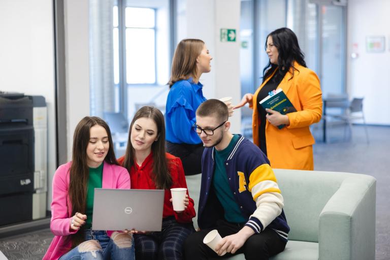 Wpływ społeczny | Uniwersytet WSB Merito Szczecin: Studenci spędzają czas w strefie relaksu, rozmawiając i pracując na laptopie.