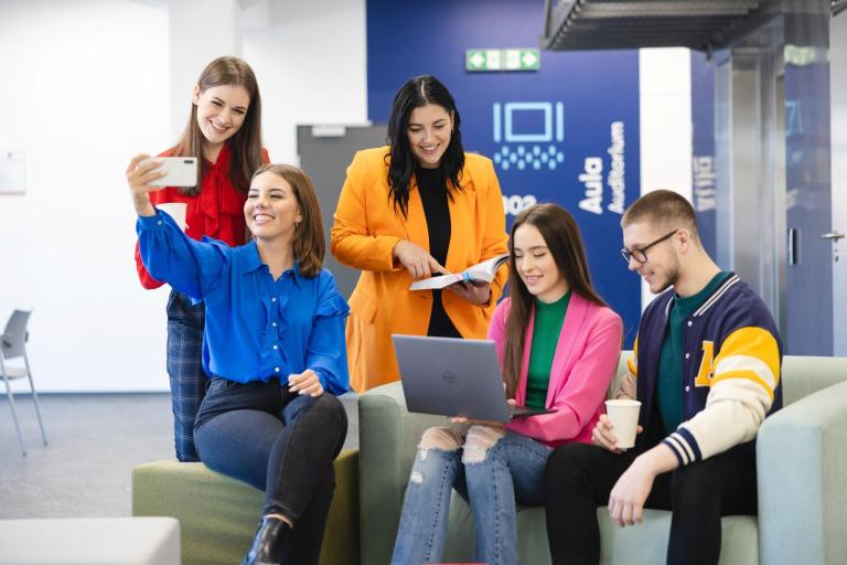 Cyfrowy uniwersytet | Uniwersytet WSB Merito Szczecin: Studenci Uniwersytetu WSB Merito robiący sobie zdjęcie i uczący się wspólnie na korytarzu uczelni
