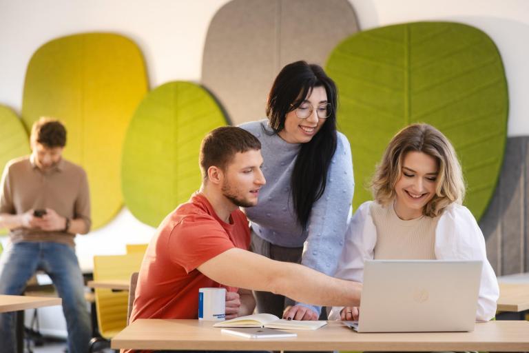 Cyfrowy uniwersytet | Uniwersytet WSB Merito Szczecin: Grupa studentów przy komputerze, jeden z nich wskazuje na ekran