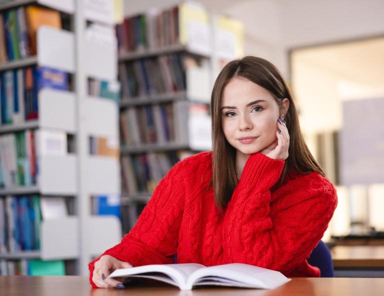 Biblioteka | Uniwersytet WSB Merito Szczecin: studentka z książką w bibliotece