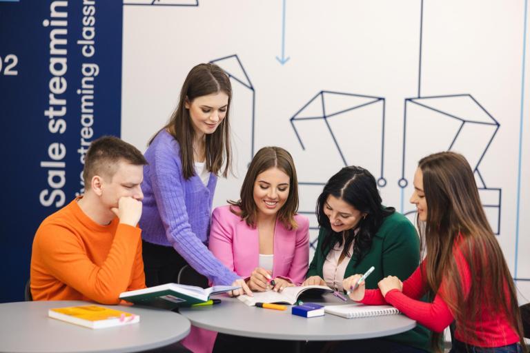 Szkoły | Uniwersytet WSB Merito Szczecin: Grupa studentów Uniwersytetu WSB Merito wspólnie pracuje nad materiałami, ucząc się i wymieniając pomysły w nowoczesnej przestrzeni edukacyjnej.