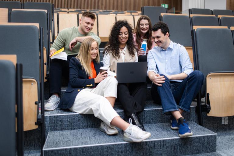 Programowanie | Studia I stopnia w Szczecinie | Uniwersytet WSB Merito Szczecin: Studenci pracują zespołowo przy laptopie w auli wykładowej.