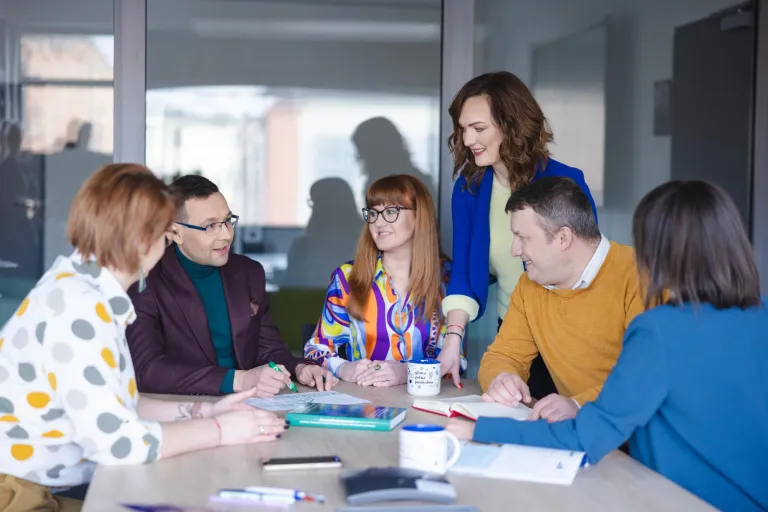 Zarządzanie | Studia II stopnia ze studiami podyplomowymi w Szczecinie | Uniwersytet WSB Merito Szczecin: Grupa osób dyskutuje przy stole w sali konferencyjnej.