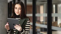 Prawo i finanse w administracji publicznej | Studia II stopnia w Toruniu | Uniwersytet WSB Merito w Toruniu: Główna grafika: Toruń - studia I stopnia - Studentka pozująca do zdjęcia z tabletem