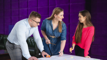E-marketing | Studia I stopnia w Toruniu | Uniwersytet WSB Merito w Toruniu: Główna grafika: Toruń - studia I stopnia - grupa uśmiechniętych studentów rozmawiająca przy projekcie