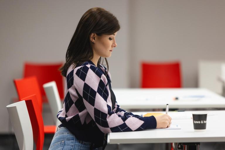 Stypendia i zniżki | Uniwersytet WSB Merito w Toruniu: Studentka notująca w zeszycie