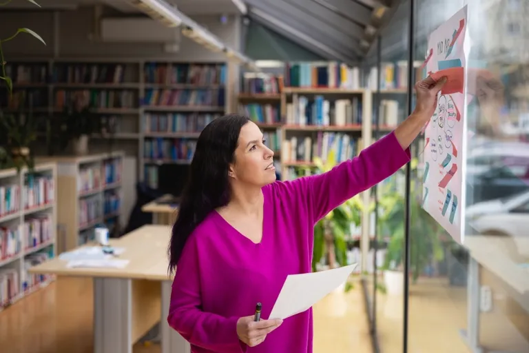 Marketing i sprzedaż | Studia I stopnia w Toruniu | Uniwersytet WSB Merito w Toruniu: Główna grafika: Toruń - studia I stopnia - studentka pracująca przy tablicy w bibliotece