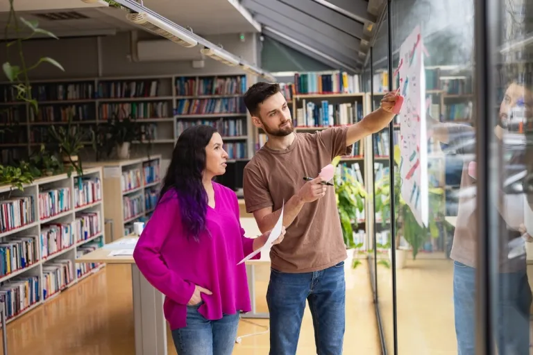 Turystyka i rekreacja | Studia I stopnia w Toruniu | Uniwersytet WSB Merito w Toruniu: Główna grafika: Toruń - studia I stopnia -dwójka studentów w bibliotece