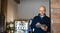 Akademia profesjonalnego coacha | Studia podyplomowe w Warszawie | Uniwersytet WSB Merito Warszawa: mężczyzna trzymający tablet w ręce