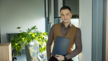 Employer Branding | Studia podyplomowe w Warszawie | Uniwersytet WSB Merito Warszawa: Student WSB Merito trzyma dyplom w ręce z uśmiechem na twarzy
