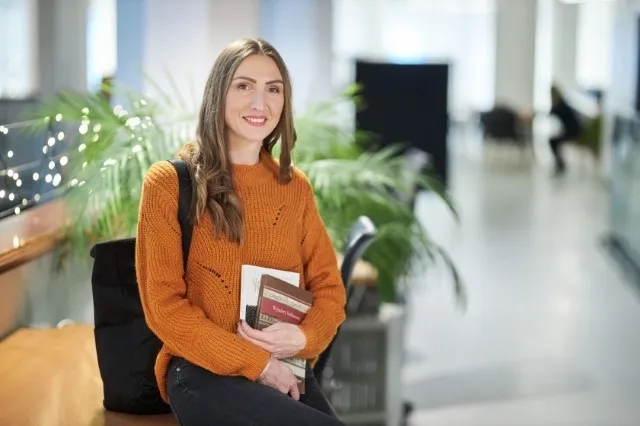 Customer Experience | Studia II stopnia w Warszawie | Uniwersytet WSB Merito Warszawa: Siedząca studentka z książkami