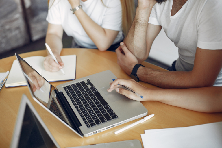 Business Intelligence & Information Management | Studia podyplomowe we Wrocławiu | Uniwersytet WSB Merito we Wrocławiu: Grupa osób pracuje wspólnie przy laptopie, zapisując notatki