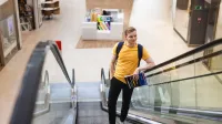 Logistyka e-commerce | Studia II stopnia we Wrocławiu | Uniwersytet WSB Merito we Wrocławiu: student na schodach ruchomych