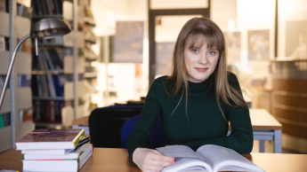 Język angielski w środowisku biznesowym | Studia I stopnia we Wrocławiu | Uniwersytet WSB Merito we Wrocławiu: Wrocław - język angielski w środowisku biznesowym - studentka w bibliotece czytająca książkę