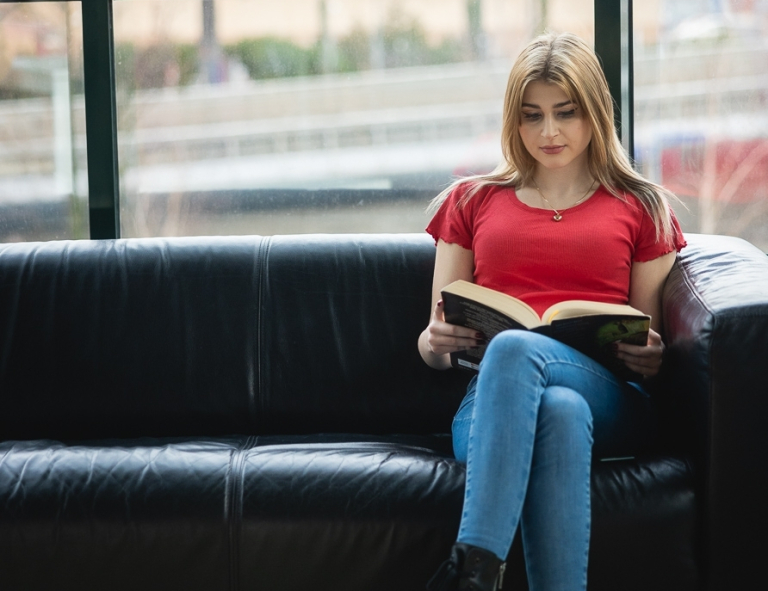 Project management | Studia II stopnia ze studiami podyplomowymi  | Uniwersytet WSB Merito we Wrocławiu: studentka siedząca na kanapie i czytająca książkę