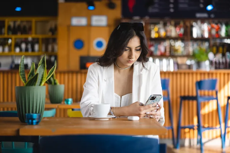 Digital marketing | Studia II stopnia we Wrocławiu | Uniwersytet WSB Merito we Wrocławiu: studentka w kawiarni patrząca w telefon