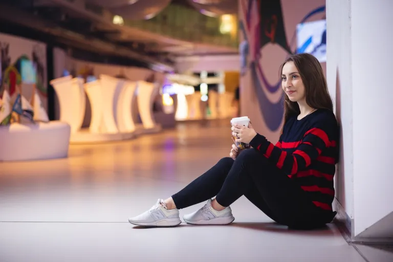 Logistyka obronna i operacyjna | Studia I stopnia we Wrocławiu | Uniwersytet WSB Merito we Wrocławiu: studentka siedząca na ziemi i pijąca kawę